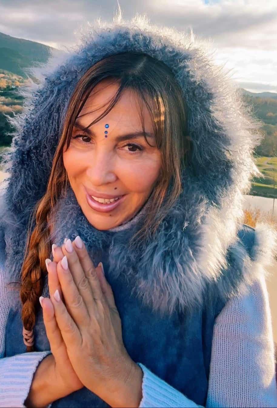 Amita in posizione di namasté, mani giunte, abito invernale di pelliccia